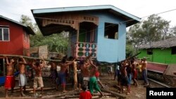 Residents lift a house damaged by Typhoon Rammasun in Batangas city, south of Manila, July 17, 2014.
