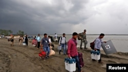 Polling officers carry electronic voting machine (EVM) towards their vehicles after arriving on a ferryboat in Nimatighat, Jorhat district, in the northeastern Indian state of Assam, India, Apr. 9, 2019.