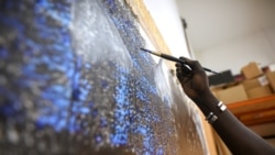Senegalese artist Omar Ba paints on a canvas hanging from the wall of his studio in Bambilor, Senegal on March 12, 2021. REUTERS/ Cooper Inveen