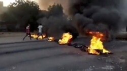 People walk past burning objects lying on the streets of Kartoum, Sudan, amid reports of a coup, Oct. 25, 2021, in this still image from video obtained via social media.