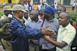 Uganda's main opposition leader Kizza Besigye (2nd R, blue cap) and his supporters are blocked by policemen during a Walk to Work protest in the Kasangati suburb near Uganda's capital Kampala, Uganda, October 18, 2011.