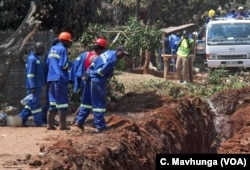 Workers try to unblock a sewer pipe in Harare, Zimbabwe, Sept. 11, 2018, which residents say has been like that for at least three months.