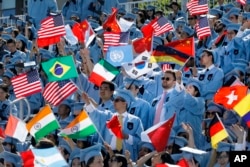 Students in the School of International and Public Affairs wave flags at Columbia University's commencement, May 22, 2019 in New York. (AP Photo/Mark Lennihan)