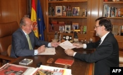 Spain's King Juan Carlos (L) hands over a letter of abdication to Spain's Prime Minister Mariano Rajoy at the Zarzuela Palace in Madrid.