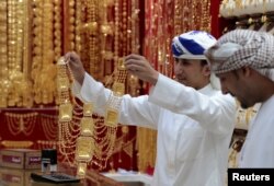 An employee shows a customer gold jewellery in a shop at the Gold Souq in Dubai, United Arab Emirates, March 24, 2018.