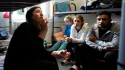 Boshra al-Moallem, second left, sits in a room with her two sisters and brother-in-law at a refugee center in Bialystok, Poland, Sept. 29, 2021.