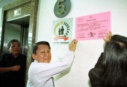 Jaksa dari Kejaksaan Agung menempelkan pengumuman penyitaan di gedung perkantoran Jakarta yang merupakan rumah bagi beberapa yayasan amal Soeharto pada 21 Juli. (Foto: Reuters)
