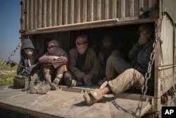 Men ride in the back of a truck that is part of a convoy evacuating hundreds out of the last territory held by Islamic State militants in Baghuz, eastern Syria, Feb. 20, 2019.