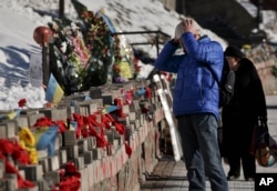 FILE - A man looks at pictures of victims of the Maidan Square protests placed in Kyiv, Ukraine, Feb. 17, 2015.
