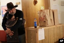 Rod Green, right, hugs a friend at By His Grace, a food pantry affiliated with Sutherland Springs Baptist Church in Sutherland Springs, Texas, Nov. 10, 2017.