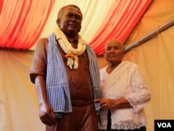 ម្ដាយលោកកែម ឡីឈរក្បែររូបសំណាកស្ពាន់តំណាងលោកកែម ឡីអ្នកវិភាគកិច្ចអភិវឌ្ឍន៍សង្គមដែលត្រូវខ្មាន់កាំភ្លើងបាញ់ស្លាប់ នៅស្រុកកំណើតលោកនៅខេត្តតាកែវ នៅថ្ងៃអាទិត្យ ទី១៧ ខែតុលា ឆ្នាំ២០១៦។(ឡេង ឡែន/VOA)