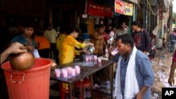 FILE - An Indian auto rickshaw driver, right, drinks sweetened water being freely distributed by the wayside on a hot summer afternoon in New Delhi, India, June 5, 2017.