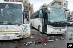 A photo released by the Syrian official news agency SANA shows blood-soaked streets and several damaged buses in a parking lot at the site of twin explosions in Damascus, Syria, March 11, 2017.