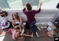 FILE - Immigrants from Honduras seeking asylum wait on the Gateway International Bridge, which connects the United States and Mexico, in Matamoros, Mexico, June 24, 2019.