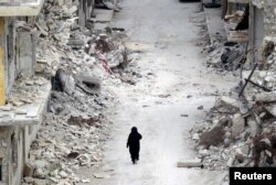 A woman walks past damaged buildings in the rebel-controlled area of Maaret al-Numan town in Idlib province, Syria on May 13, 2016. (Reuters)