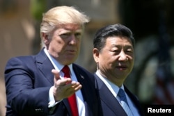 FILE - U.S. President Donald Trump and China's President Xi Jinping chat as they walk along the front patio of the Mar-a-Lago estate after a bilateral meeting in Palm Beach, Florida, April 7, 2017.