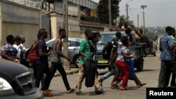 Des passants courent alors qu'il quitte le port d'Abidjan après avoir entendu des tirs, en Côte d'Ivoire, le 18 janvier 2017.