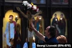 NORTH MACEDONIA -- A man touches the wooden statue of Jesus Christ on a cross at the main Orthodox church St. Kliment in Skopje on Good Friday, April 26, 2019