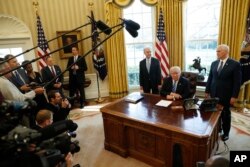 FILE - President Donald Trump, flanked by Health and Human Services Secretary Tom Price, left, and Vice President Mike Pence speaks to the media regarding the health care reform bill, in the Oval Office of the White House, in Washington, March 24, 2017.