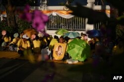 FILE - People gather holding a portrait of Thailand's King Maha Vajiralongkorn along a sidewalk near the Grand Palace in Bangkok on May 3, 2019, ahead of King Vajiralongkorn's coronation which will take place from May 4 to 6.