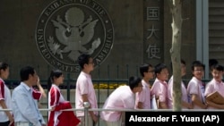 Chinese students wait outside the U.S. Embassy for their visa application interviews in Beijing, China.