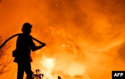 A firefighter battles a wildfire as it burns along a hillside near homes in Santa Paula, California, Dec. 5, 2017.