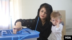 A Kurdish woman carries her baby while voting at a polling station during parliamentary elections in Sulaimaniah, Iraq, September 30, 2018. (Photo: R Majeed/VOA/Kurdish)