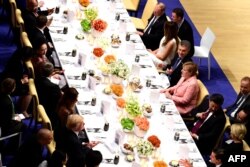 FILE - German Chancellor Angela Merkel, center right, flanked by, from left, Russia's President Vladimir Putin, U.S. first lady Melania Trump, Argentinia's President Mauricio Macri and China's President Xi Jinping, attends a banquet after a concert at the Elbphilharmonie concert hall during the G-20 summit in Hamburg, Germany, July 7, 2017.