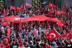 Turkish citizens wave their national flags as they protest against the military coup outside Turkey's parliament near the Turkish military headquarters in Ankara, Turkey, Saturday, July 16, 2016.