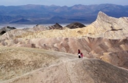 In this April 11, 2010 file photo, tourists walk along a ridge at Death Valley National Park, Calif. Preliminary data show that Death Valley set the world record for hottest month in July 2018.