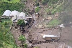 Seorang pria berdiri di tengah reruntuhan bangunan menyusul banjir bandang di Batu, Jawa Timur, Jumat, 5 November 2021. (AP)
