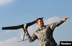 U.S. soldier Randell Atkinson poses in the starting position with a Raven drone during its official presentation by the German and U.S. Unmanned Aerial Systems at the U.S. military base in Vilseck-Grafenwoehr, Germany, Oct. 8, 2013.