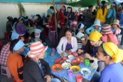 រូបឯកសារ៖ កម្មករ​រោងចក្រ​កាត់​ដេរ​សម្លៀកបំពាក់​កម្ពុជា​កំពុង​ទទួល​ទាន​អាហារ​ពេល​ថ្ងៃ​ត្រង់​នៅ​តូប​លក់​ម្ហូប​អាហារ​មួយ នៅ​ខាង​មុខ​រោងចក្រ​ដែល​ពួកគេ​ធ្វើការ ភ្នំពេញ ថ្ងៃទី៨ ខែឧសភា ឆ្នាំ២០១៤។