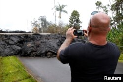 A resident of the Leilani Estates subdivision takes photos of a lava flow near his home during eruptions of the Kilauea volcano, Hawaii, May 8, 2018.