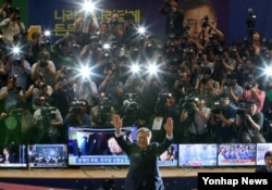 문재인 한국 대통령 당선인이 9일 오후 서울 여의도 국회의원회관 대회의실에 마련된 당 개표상황실을 찾아 두 손을 번쩍 들어 인사하고 있다.