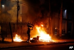 FILE - A protester carries a chair to a fire outside the Congress building during clashes between police and protesters opposing a constitutional amendment that would allow the election of a president to a second term, in Asuncion, Paraguay, March 31, 2017.