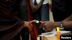 Seorang petugas tengah memeriksa sidik jari salah seorang pemilih di Daura, barat laut Nigeria, 28 Maret 2015 (REUTERS/Akintunde Akinleye)