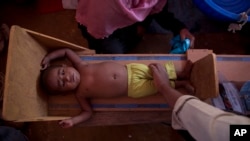 A volunteer measures the height of a Rohingya child at a health center at Balukhai refugee camp near Cox's Bazar, Bangladesh, Jan. 28, 2018.