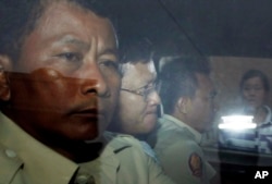 លោក នី ចរិយា (កណ្តាល) អតីត​មន្ត្រី​របស់​អង្គការ​អាដហុក និង​ជា​សមាជិក​ម្នាក់​នៃ​គណៈកម្មាការ​រៀបចំ​ការ​បោះឆ្នោត កំពុង​ត្រូវបាន​បញ្ចូន​ខ្លួន​ទៅ​អង្គភាព​ប្រឆាំង​អំពើ​ពុក​រលួយ​ បន្ទាប់​ពី​បាន​ចូលបង្ហាញ​ខ្លួន នៅ​សាលាដំបូង​រាជធានី​ភ្នំពេញ កាលពី​ថ្ងៃទី៣០ ខែមេសា ឆ្នាំ២០១៦។ (AP Photo/Heng Sinith)