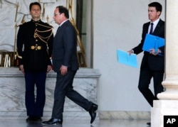 French President Francois Hollande, center, and Prime Minister Manuel Valls, right, walk through the lobby of the Elysee Palace after the weekly cabinet meeting, in Paris, Nov. 18, 2015.