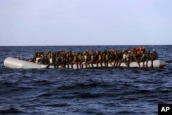 Sub-Saharan migrants crowd a rubber boat as they are rescued by members of Proactive Open Arms NGO, in the Mediterranean Sea, about 22 miles north of Zumarah, Libya, Jan. 27, 2017. Italy's coast guard, meanwhile, says it picked up about 1,000 migrants.