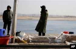 中国渔民在丹东的河边卖鱼，河对岸是朝鲜边境城镇新义州。中国东北受朝鲜之害(2013年2月7日)