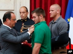 Presiden Perancis Francois Hollande (kiri) memberikan penghargaan 'Legion of Honor' kepada Alek Skarlatos, seorang Tentara Amerika dari Roseburg, Oregon, disaksikan oleh tentara Angkatan Udara AS Spencer Stone (kanan) di istana Elysee, Senin, 24 Agustus 2015 di Paris, Perancis.