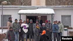 Asylum seekers stand outside an accommodation at a refugee holding centre in the town of Bad Belzig some 135 km (84 miles) south-west of Berlin, December 12, 2012.