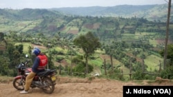 Motorcycle rider is seen with Kenya's Mau Forest village in the background.