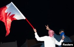 FILE - Sunni protesters wave a Bahraini flag as they protest, demanding the government end chaos in their country, in Hamad Town south of Manama, Dec. 24, 2011.