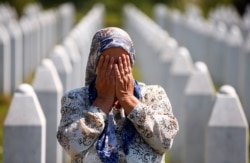 A woman prays at a graveyard, ahead of a mass funeral in Potocari near Srebrenica, Bosnia and Herzegovina July 11, 2020. Bosnia marks the 25th anniversary of the massacre of more than 8,000 Bosnian Muslim men and boys, with many relatives unable to attend