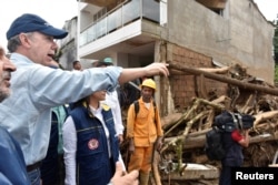 Colombia's President Juan Manuel Santos visits a flooded area after heavy rains caused several rivers to overflow, pushing sediment and rocks into buildings and roads in Mocoa, April 1, 2017.