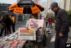 A man looks at a newsstand with a copy of the day's Global Times displayed on a basket in Beijing, China, Tuesday, April 5, 2016.