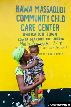 Mamie Harris, a caregiver at Liberia’s Hawa Massaquoi transit center in Unification Town, Margibi County, holds 18-month-old Agnes. The center, run by the government with UNICEF support, aids children affected by Ebola. (© UNICEF /Jallanzo)